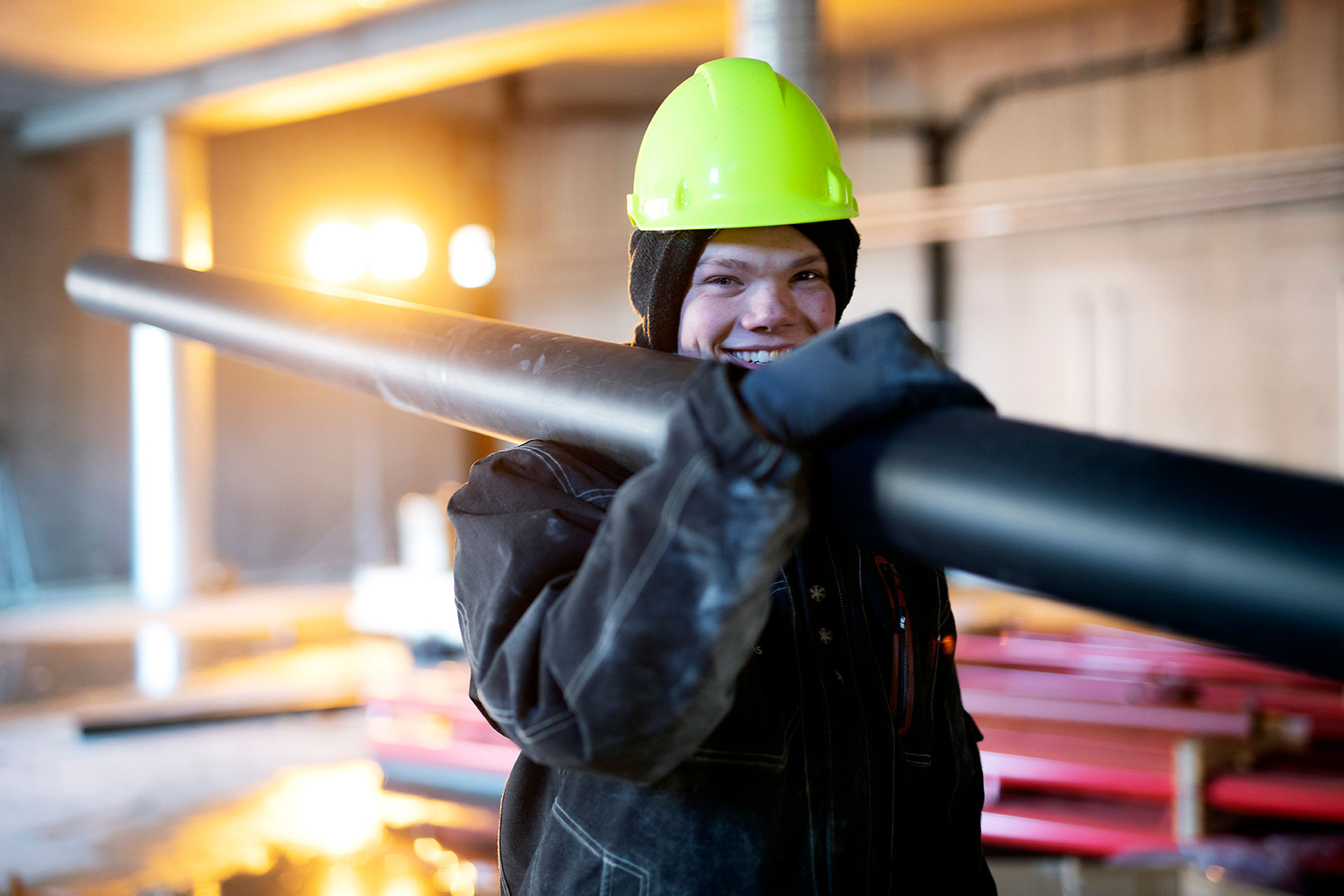 Rørlegger Liene på jobb - lærling med rør over skulder.